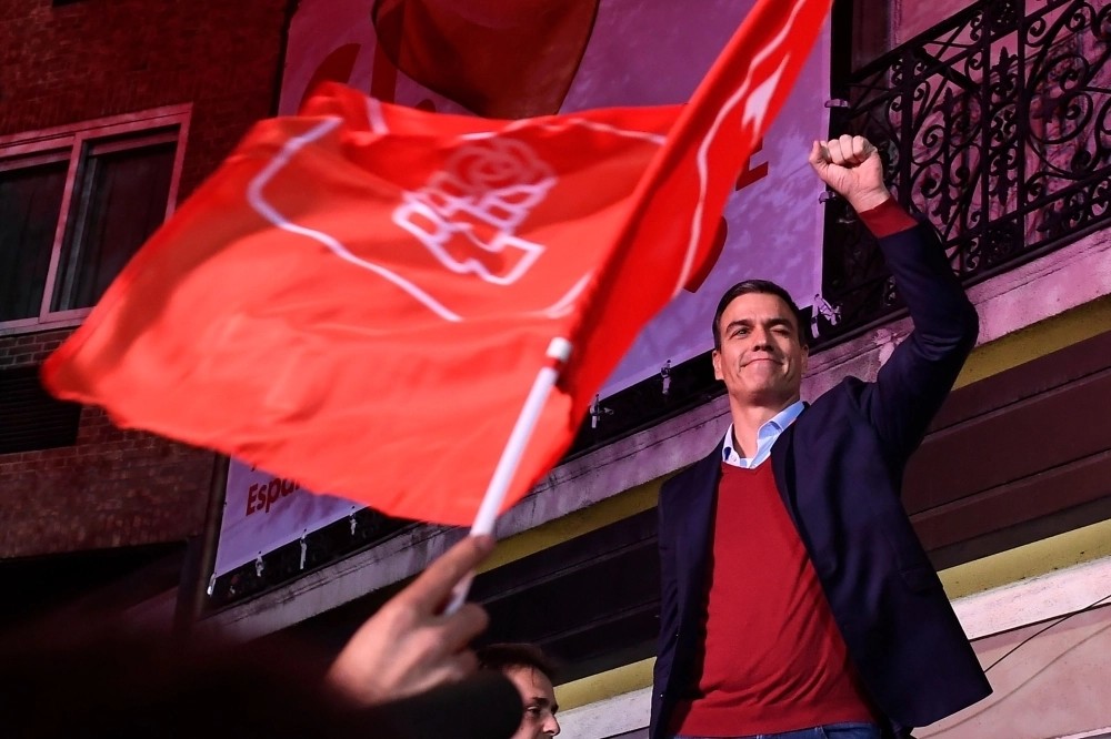 Pedro Sánchez celebra con el puño en alto ante una bandera del PSOE