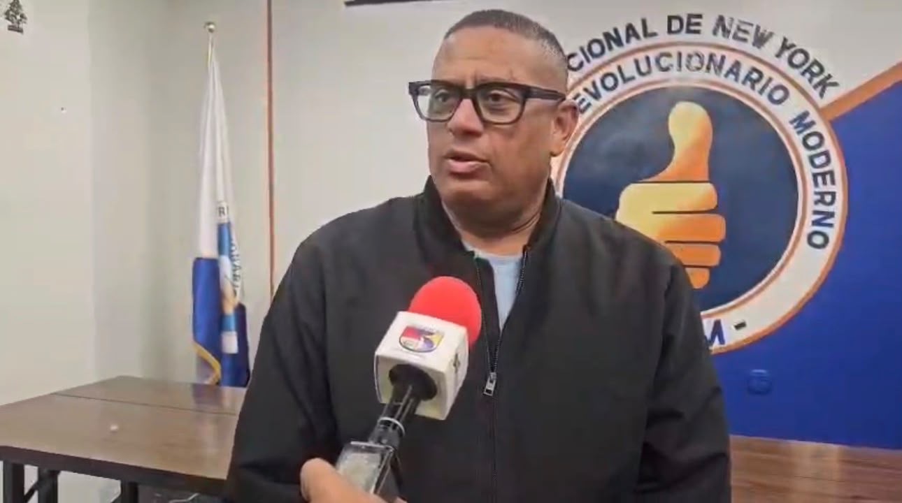 Dirigente del PRM de Nueva York ante el logo de la seccional